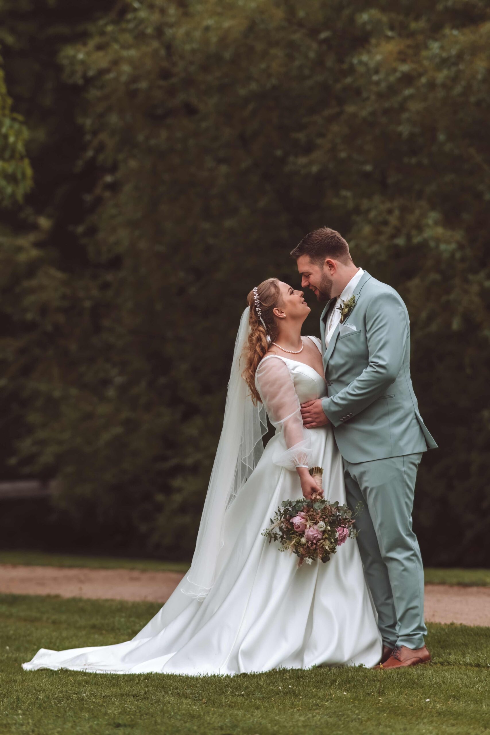 Glückliches Pärchen schaut sich verliebt in die Augen im Celler Schlossgarten - Hochzeitsfotografie